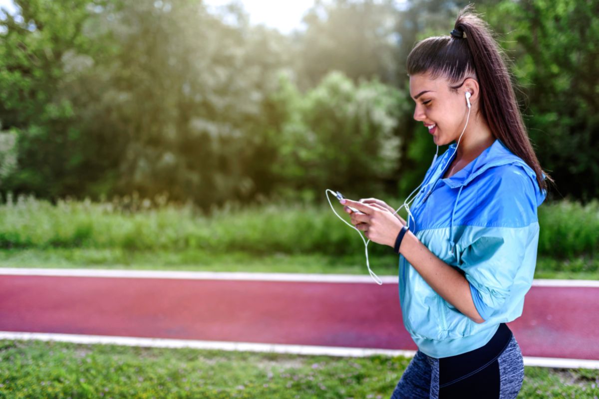 Jogging girl with rain jacket looking at her cellphone.